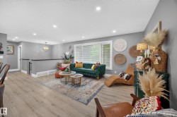 Open-concept living space featuring light wood-finish flooring, recessed ceiling lighting, and a prominent window with white blinds - 