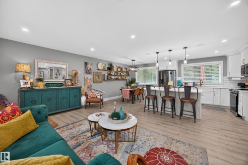 Open-concept living space featuring wood-finish flooring, recessed lighting, and a white kitchen with an island and pendant lights - 43 Burnham Place, St. Albert, AB 