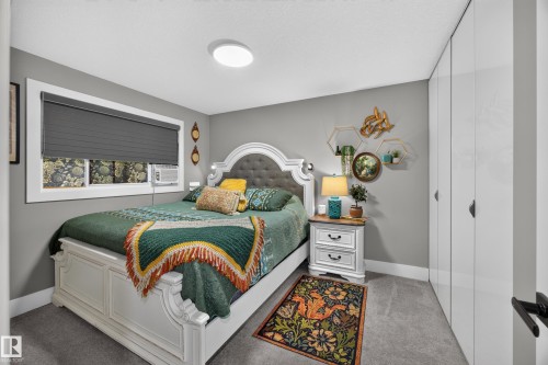Carpeted bedroom featuring a large window with privacy blinds, recessed lighting, and built-in closet storage with modern flat-panel doors - 43 Burnham Place, St. Albert, AB 