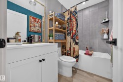Bathroom featuring a white vanity with cabinet storage, matte black faucet, and a large wall mirror - 