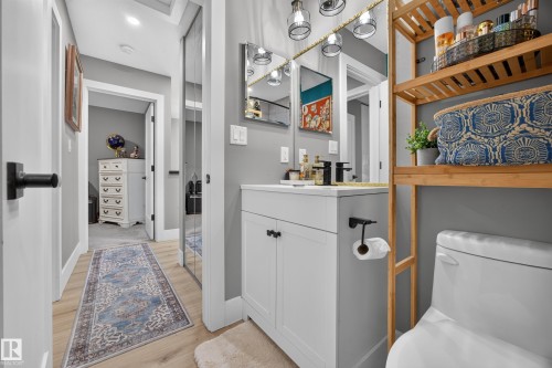 Bathroom featuring a white vanity with black hardware, coordinating black faucet, and a wall-mounted mirror with integrated lighting - 43 Burnham Place, St. Albert, AB 