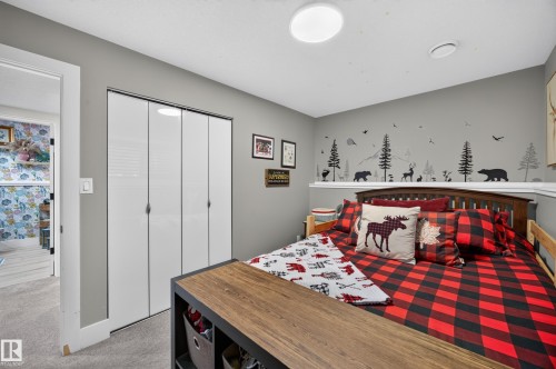 Bedroom featuring a built-in closet with bi-fold doors, a wood-finish headboard, and wall-mounted art - 43 Burnham Place, St. Albert, AB 