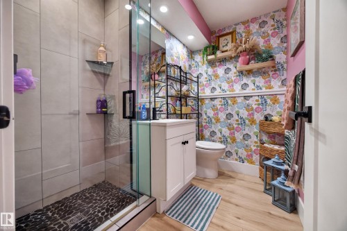 Full bathroom featuring a glass-enclosed shower with pebble-style flooring and light-toned wall tiling - 43 Burnham Place, St. Albert, AB 