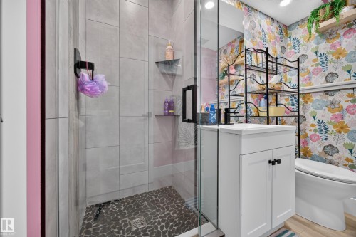 Modern bathroom featuring a glass-enclosed shower with pebble-finish flooring and gray tile surround - 43 Burnham Place, St. Albert, AB 