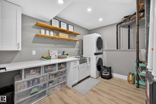 Dedicated utility space featuring wood-finish flooring, white cabinetry, open wood shelving, a utility sink, and recessed lighting - 43 Burnham Place, St. Albert, AB 