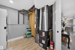 Utility space featuring wood-finish flooring, a stacked washer and dryer, and a Goodman furnace system - 