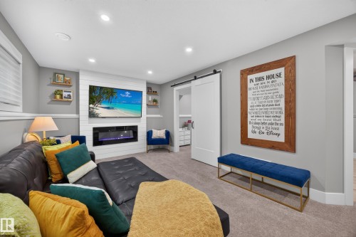 Living area featuring recessed lighting, a media wall with built-in fireplace, and wood-finish floating shelves - 43 Burnham Place, St. Albert, AB 