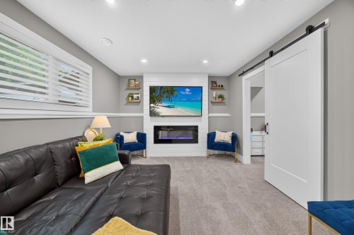 Spacious room featuring a wall-mounted television above an electric fireplace, recessed lighting, and light gray carpeting - 43 Burnham Place, St. Albert, AB 