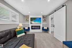 Spacious room featuring a wall-mounted television above an electric fireplace, recessed lighting, and light gray carpeting - 