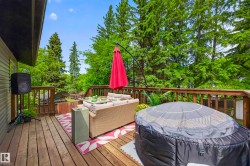 Spacious wood deck featuring a protective railing and surrounded by mature trees - 