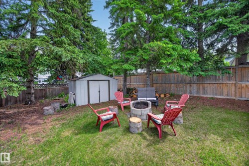 Expansive backyard featuring a lush lawn, mature evergreen trees, and a wooden privacy fence - 43 Burnham Place, St. Albert, AB 