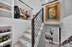 Modern staircase featuring wood-finish treads with patterned risers, a black metal railing, and shiplap wall paneling - 