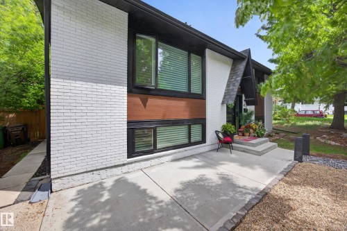 Modern exterior featuring white painted brick, rich wood-finish siding, and black trim around large windows - 43 Burnham Place, St. Albert, AB 