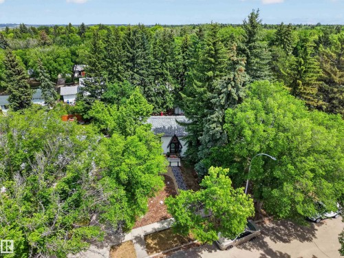 Tree-lined residential property featuring a distinctive A-frame roofline and a dark-toned exterior - 43 Burnham Place, St. Albert, AB 