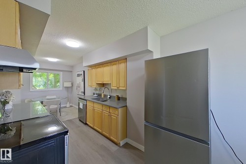 Kitchen featuring light wood-finish cabinetry, stainless steel appliances, and grey countertops - 176 Centennial Court, Edmonton, AB 