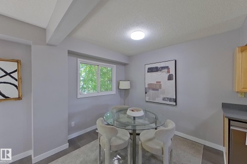Dining area featuring wood-finish flooring, a white trim window, light gray wall tones, a flush-mount ceiling light, and a built-in countertop with cabinetry - 176 Centennial Court, Edmonton, AB 