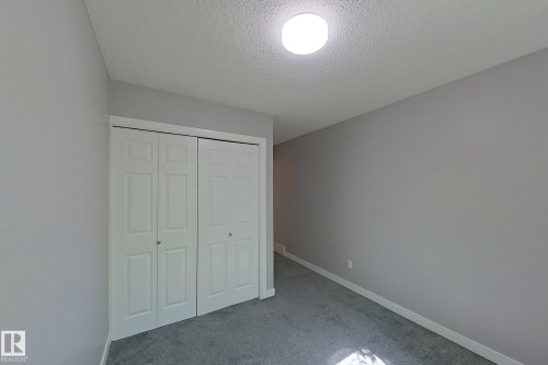 Neutral gray walls with white trim, featuring a bi-fold closet with panel doors and a flush-mount ceiling light - 176 Centennial Court, Edmonton, AB 