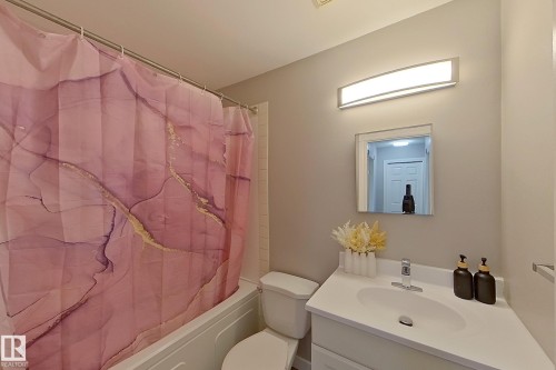 Bathroom featuring a white vanity with an integrated sink, polished chrome faucet, and a wall-mounted rectangular mirror - 176 Centennial Court, Edmonton, AB 