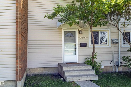 Exterior entrance with concrete steps, a white storm door, and beige siding - 176 Centennial Court, Edmonton, AB 