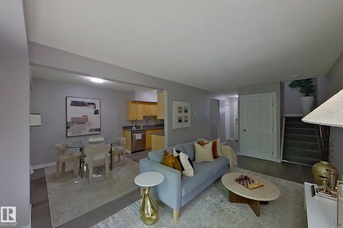 Open-concept living space featuring wood-finish flooring, a dining area with a glass-top table, and a kitchen with light wood cabinetry and stainless steel appliances - 176 Centennial Court, Edmonton, AB 