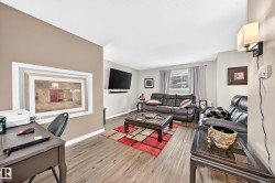 Open-concept living area featuring wood-finish flooring, a neutral color palette, and a wall-mounted sconce - 
