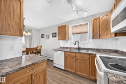 Kitchen featuring wood-finish cabinetry, patterned countertops, and white tile backsplash - 