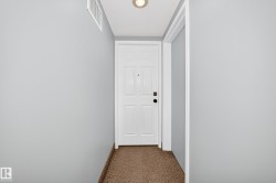 Entryway featuring a paneled door with dark hardware, recessed lighting, a white air vent, and textured carpeting - 
