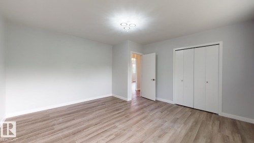 Spacious room featuring wood-finish flooring, light grey painted walls, white baseboards, and a contemporary ceiling light fixture - 11744 135 Street, Edmonton, AB - Indoor Photo Showing Other Room
