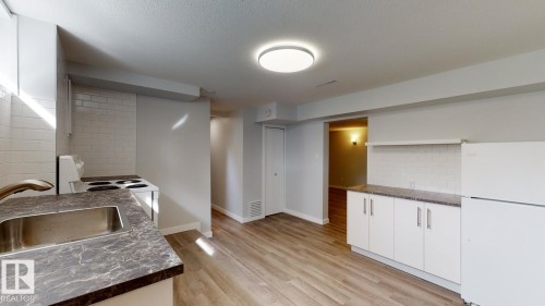 Kitchen featuring wood-finish flooring, white cabinetry, and a subway tile backsplash - 11744 135 Street, Edmonton, AB - Indoor