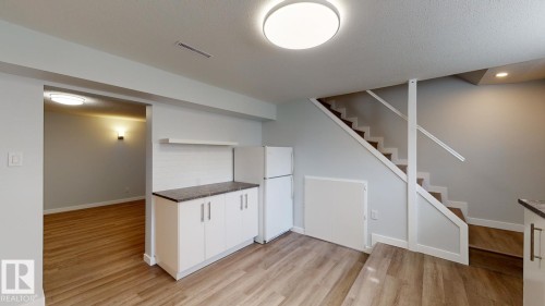 Open-concept living area with wood-finish flooring, white cabinetry, a built-in refrigerator, and a tiled backsplash - 11744 135 Street, Edmonton, AB - Indoor Photo Showing Other Room