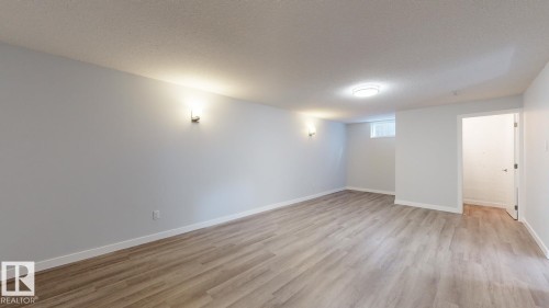 Spacious interior room featuring wood-finish flooring, light grey walls, and a white ceiling - 11744 135 Street, Edmonton, AB - Indoor Photo Showing Other Room