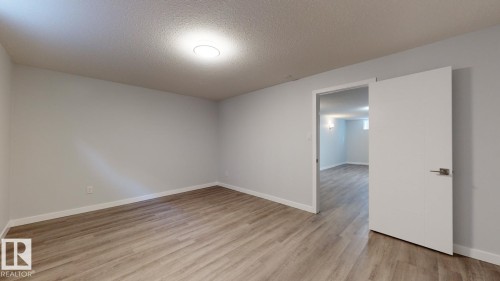 Spacious interior room featuring wood-finish flooring, light gray walls, and white trim - 11744 135 Street, Edmonton, AB - Indoor Photo Showing Other Room