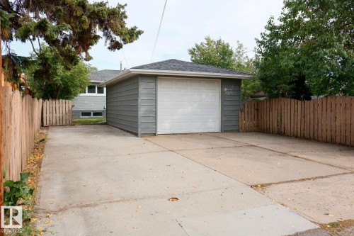 Detached garage with horizontal siding and a white overhead door, offering direct access via a concrete driveway - 11744 135 Street, Edmonton, AB - Outdoor With Exterior
