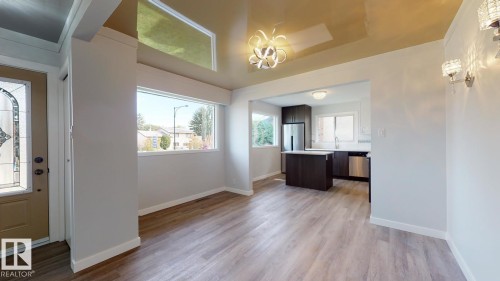 Open-concept living area featuring wood-finish flooring, a contemporary chandelier, and decorative wall sconces - 11744 135 Street, Edmonton, AB - Indoor Photo Showing Other Room