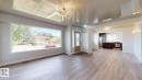Spacious living area featuring light wood-finish flooring, a large picture window, a decorative entry door with glass inserts, and a modern ceiling light fixture - 11744 135 Street, Edmonton, AB  - Indoor 