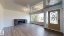Spacious living area featuring a contemporary fireplace with dark tile surround, light wood-finish flooring, and high vaulted ceilings - 11744 135 Street, Edmonton, AB  - Indoor Photo Showing Living Room With Fireplace 