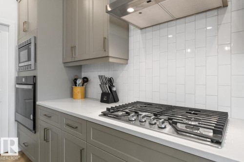 Kitchen featuring a built-in gas range, white subway tile backsplash, and light gray cabinetry - 117 Paisley Gate Gate, Edmonton, AB 