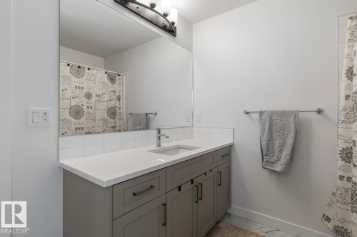 Bathroom featuring a large vanity with gray cabinetry and brushed nickel hardware, a white countertop with an integrated sink, and a chrome faucet - 117 Paisley Gate Gate, Edmonton, AB 