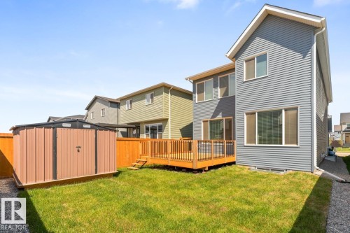 Rear exterior showcasing a wood deck with black railings, a grass lawn, and a metal storage shed - 117 Paisley Gate Gate, Edmonton, AB 