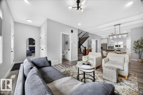Open-concept living area featuring wood-finish flooring, recessed lighting, and a modern chandelier - 424 Black Stone Link, Leduc, AB 