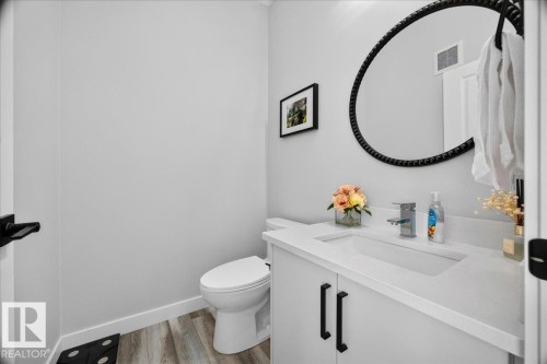 Powder room featuring a white vanity with integrated sink, chrome faucet, white countertop, and black cabinet pulls - 424 Black Stone Link, Leduc, AB 