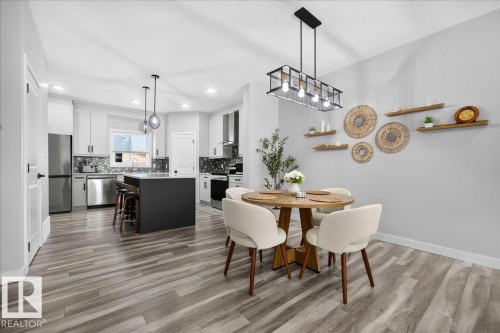 Open-concept kitchen and dining area with wood-finish flooring - 424 Black Stone Link, Leduc, AB 