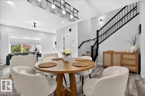 Open-concept main level featuring wood-finish flooring, recessed lighting, and a modern linear chandelier - 424 Black Stone Link, Leduc, AB 