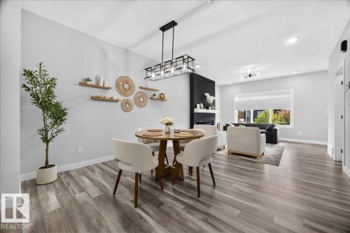 Open-concept living area featuring wood-finish flooring, recessed lighting, and a modern fireplace with a black accent wall - 424 Black Stone Link, Leduc, AB 