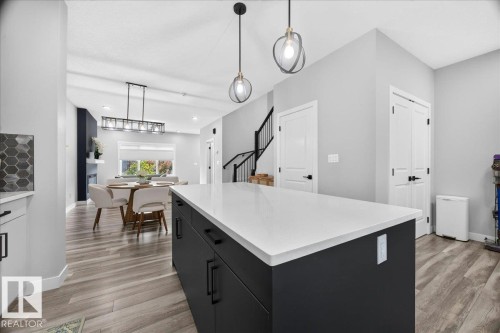 Modern kitchen island with a white countertop and dark cabinetry - 424 Black Stone Link, Leduc, AB 