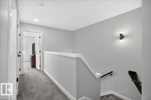Upper-level hallway featuring a carpeted floor, recessed lighting, and a modern wall sconce - 424 Black Stone Link, Leduc, AB 