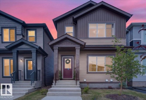 Two-story residence featuring a covered front entry with a deep red door - 424 Black Stone Link, Leduc, AB 