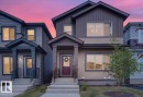 Two-story residence featuring a covered front entry with a deep red door - 424 Black Stone Link, Leduc, AB 