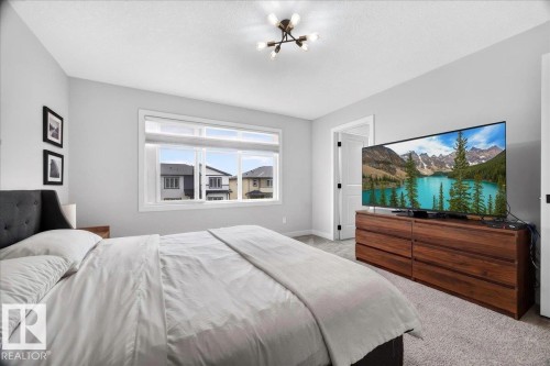 Recessed window with white trim, wood-finish flooring, light grey carpeting, and a modern ceiling light fixture - 424 Black Stone Link, Leduc, AB 