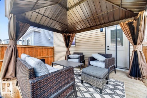 Covered wood-finish deck featuring a permanent gazebo structure with a metal roof and privacy drapes - 424 Black Stone Link, Leduc, AB 